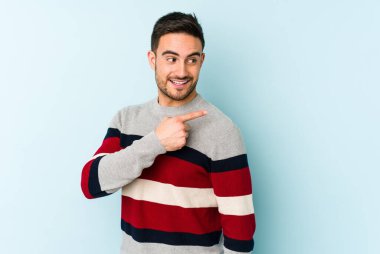 Mavi arka planda soyutlanmış genç beyaz bir adam gülümsüyor, neşeli ve keyifli görünüyor..