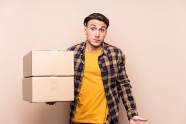 Kafkasyalı genç adam kutuları tutuyor omuzlarını silkiyor ve gözleri açık..