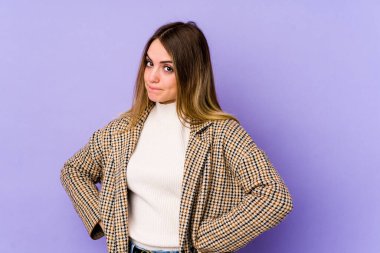 Mor arka planda soyutlanmış, kafası karışmış, şüpheli ve güvensiz genç bir beyaz kadın..