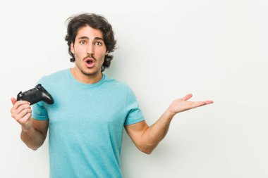 Elinde oyun kumandası tutan genç adam, avuç içinde kopya alanı tutmaktan etkilenmiş..