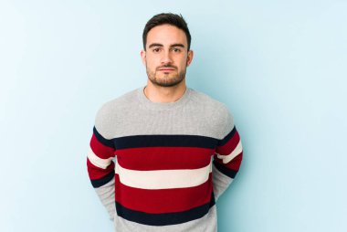 Kafkasyalı genç adam mavi arka planda izole edilmiş üzgün, ciddi yüzlü, mutsuz ve hoşnutsuz..