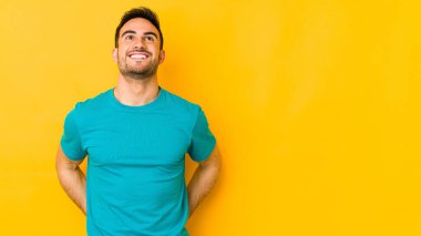Kafkasyalı genç adam sarı fırında izole edilmiş gevşemiş ve mutlu bir şekilde gülüyor, boynunda dişlerini gösteriyor..