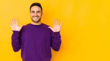 Sarı fırında izole edilmiş genç beyaz adam on numarayı elleriyle gösteriyor..