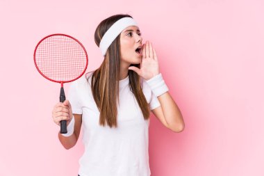 Badminton oynayan beyaz bir kadın bağırıyor ve ağzı açık bir şekilde avucunu tutuyor..