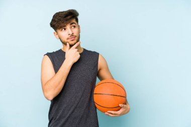 Sepet oynayan genç bir Arap şüpheli ve şüpheci bir ifadeyle yanlamasına bakıyor..