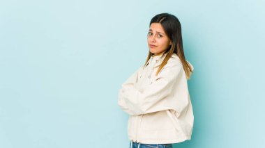 Mavi arka planda izole edilmiş genç bir kadın şüpheli, belirsiz, seni sorguluyor..