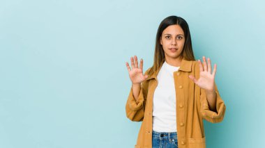 Mavi arka planda izole edilmiş genç bir kadın yakın bir tehlike nedeniyle şoka uğruyor.