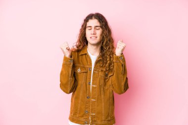 Genç, uzun saçlı adam kendini mutlu ve başarılı hisseden münzevi poz veriyor. Zafer konsepti.