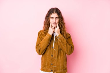 Genç, uzun saçlı adam iki seçenek arasında kuşkuyla poz veriyor..