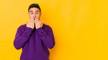 Sarı fırında izole edilmiş genç beyaz adam şok olmuş, ağzı ellerle kaplanmış, yeni bir şey keşfetmek için sabırsızlanıyor..