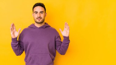 Kafkasyalı genç adam sarı fırında izole edilmiş. Elinde işaret parmaklarıyla küçük bir şey tutuyor, gülümsüyor ve kendinden emin..