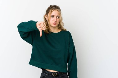 Beyaz arka planda genç beyaz bir kadın baş parmağını aşağı gösteriyor ve hoşlanmadığını ifade ediyor..