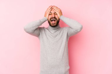Pembe arka planda izole olmuş genç, uzun saçlı adam mutlu bir şekilde ellerini başının üstünde tutarak gülüyor. Mutluluk kavramı.