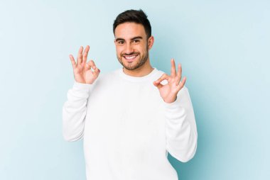 Kafkasyalı genç adam mavi arka planda izole edilmiş neşeli ve kendinden emin..