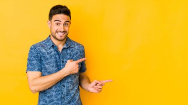 Sarı fırında izole edilmiş genç beyaz adam işaret parmağıyla fotokopi alanını işaret ederek şok oldu..