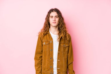 Uzun saçlı genç adam yalnız mutlu, güler yüzlü ve neşeli poz veriyor..