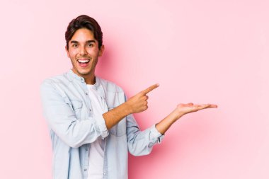 Pembe arka planda poz veren genç beyaz bir adam..