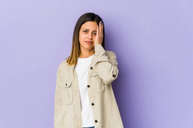 Mor arka planda izole edilmiş genç bir kadın yorgun ve uykulu. Elini başının üstünde tutuyor..