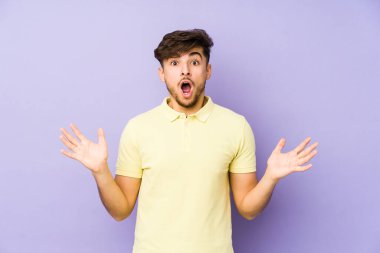 Mor arka planda kalan genç Arap bir adam zaferi ya da başarıyı kutluyor, şaşırıyor ve şok oluyor..