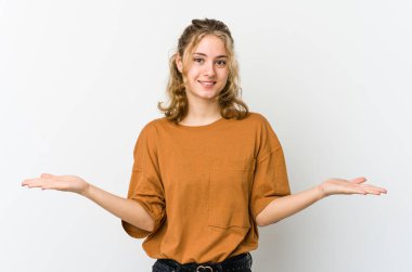 Beyaz arka plandaki genç beyaz kadın kollarıyla ölçek yapıyor, mutlu ve kendinden emin hissediyor..