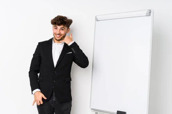 Young business coaching arabian man showing a mobile phone call gesture with fingers.