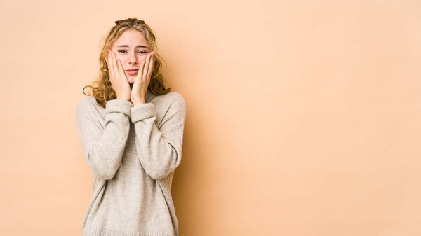 Young caucasian woman isolated on beige background whining and crying disconsolately.