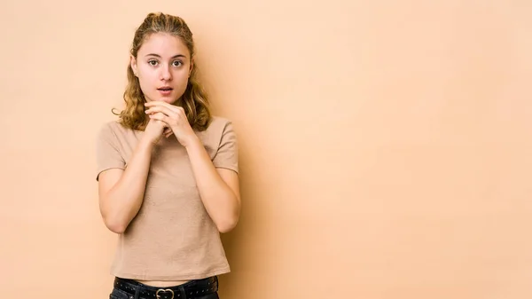 Jonge Kaukasische Vrouw Geïsoleerd Beige Achtergrond Bidden Voor Geluk Verbaasd — Stockfoto