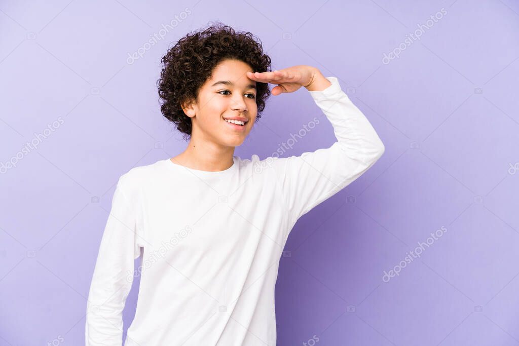 African american little boy isolated looking far away keeping hand on forehead.