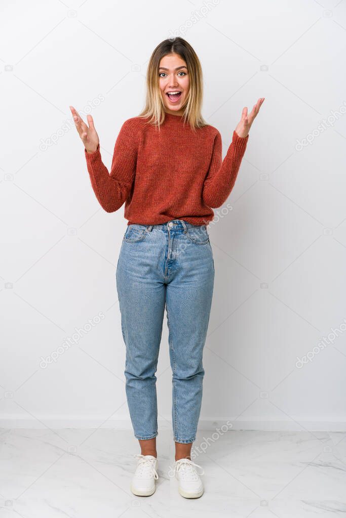 Full body young caucasian woman receiving a pleasant surprise, excited and raising hands.