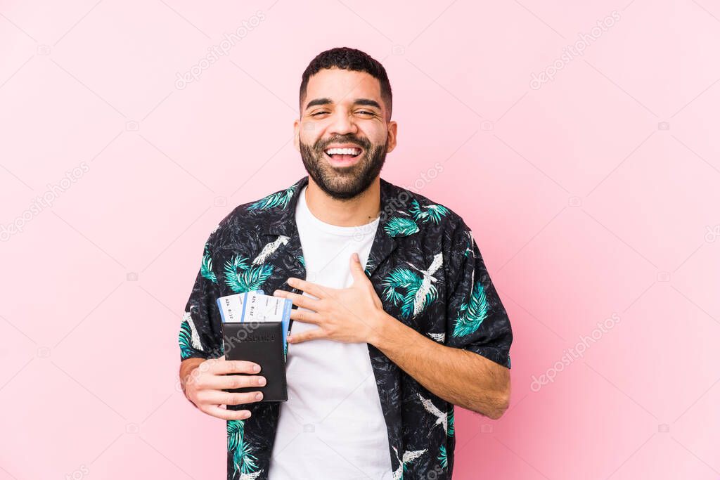 Young arabian cool man holding a boarding passes isolated laughs out loudly keeping hand on chest.