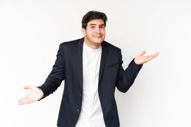 Genç iş adamı beyaz arka planda izole edilmiş. Kafası karışmış ve omuz silkiyor. Kopya alanını tutmak için..