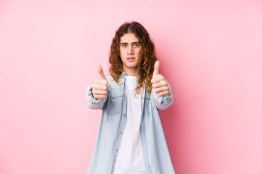 Uzun saçlı adam başparmağıyla izole poz veriyor, bir şey için tezahürat yapıyor, destek oluyor ve saygı duyuyor..