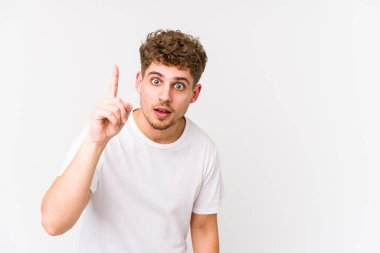 Sarışın, kıvırcık saçlı, beyaz tenli bir adam bir numarayı parmağıyla gösteriyor..