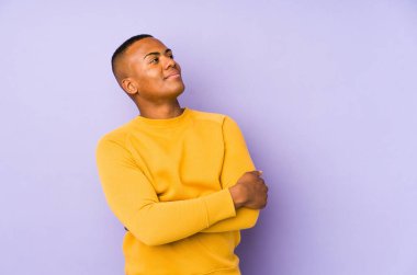 Mor arka planda izole edilmiş genç latin adam hedeflere ve amaçlara ulaşma hayali kuruyor.