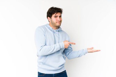 Beyaz arka planda izole edilmiş genç bir adam, avuç içinde bir kopya alanı tutarken heyecanlı..