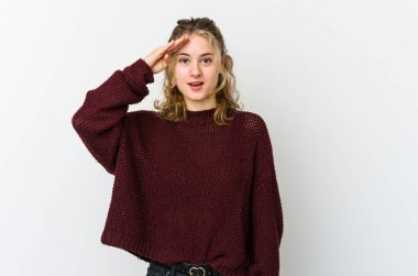 Beyaz arka plandaki genç beyaz kadın yüksek sesle bağırıyor, gözlerini açık ve ellerini gergin tutuyor..