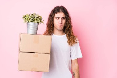 Kafkasyalı genç bir adam kutuları tek başına tutuyor. Kafası karışık ve kendinden emin değil..