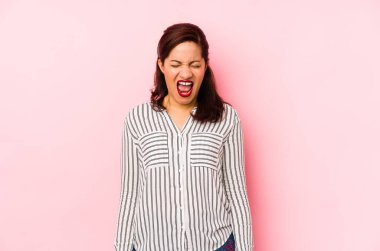 Pembe arka planda izole edilmiş orta yaşlı Latin bir kadın çok sinirli ve agresif bağırıyor..