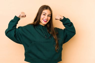 Beyazlı genç bir kadın bej arka planda izole edilmiş. Güçlü bir hareket sergiliyor. Kadınsı gücün sembolü.