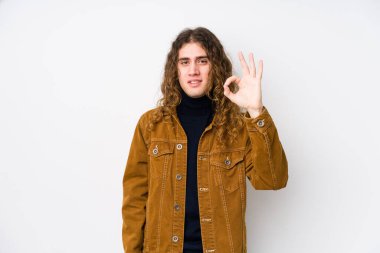 Uzun saçlı adam neşeli ve kendinden emin bir şekilde poz veriyor..