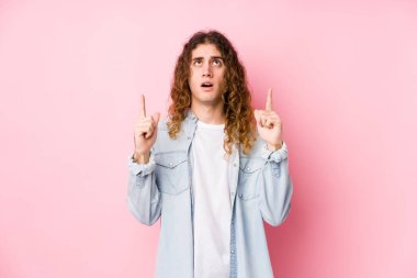 Uzun saçlı adam yalnız poz veriyor, ağzı açık bir şekilde yukarı bakıyor..