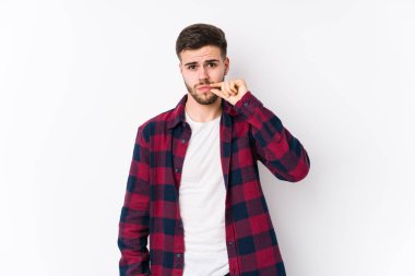 Beyaz arka planda poz veren beyaz tenli genç bir adam. Parmakları dudaklarında bir sır saklıyor..