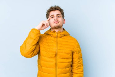 Sarışın, kıvırcık saçlı, beyaz tenli bir adam tapınağı işaret ediyor, düşünüyor ve bir işe odaklanıyor..