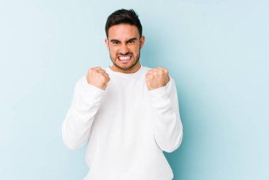 Mavi arka planda izole edilmiş genç beyaz adam gergin elleriyle çığlık atıyor..