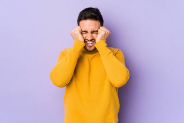 Mor arka planda izole edilmiş genç beyaz bir adam ağlıyor, bir şeyden memnun değil, acı ve kafa karışıklığı konsepti..