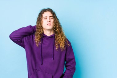 Uzun saçlı adam yalnız poz veriyor. Kafasının arkasına dokunuyor, düşünüyor ve bir seçim yapıyor..