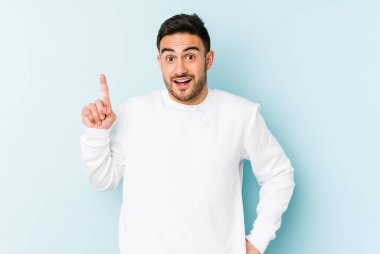 Kafkasyalı genç bir adam mavi arka planda izole edilmiş. Bir fikri, ilham verici bir fikri var..