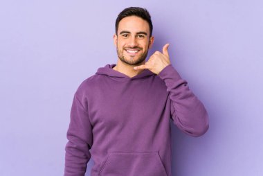 Mor arka planda izole edilmiş genç beyaz adam parmakları olan bir cep telefonu hareketi gösteriyor..