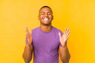 Sarı arka planda izole edilmiş genç latin adam neşeli bir şekilde gülüyor. Mutluluk kavramı.