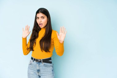 Genç Hintli kadın mavi arka planda izole edildi. Yakın bir tehlike nedeniyle şoka uğruyor.